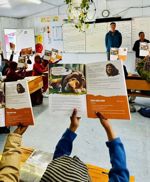 Lernende halten während einer Leseaktivität im Klassenzimmer offene Bücher hoch.
