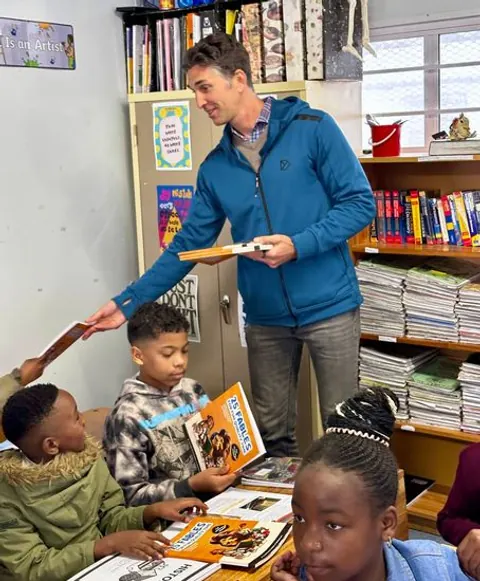 Eine Lehrerin teilt Bücher mit Lernenden im Klassenzimmer.