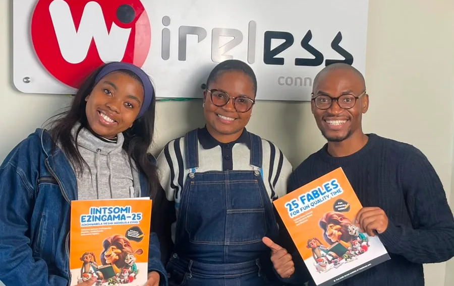 Anelisa Kana, Andisiwe Mbelekane and Lwamkelo Tshikini holding English and isiXhosa FableReads books at The Wireless.